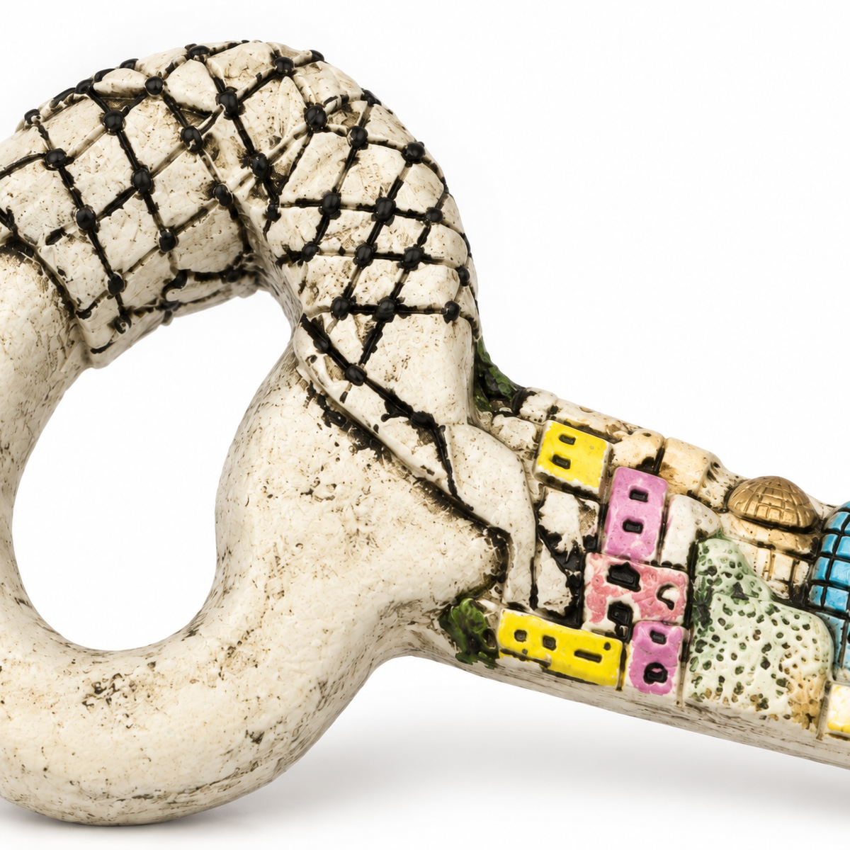 Close view of the keffiyeh-patterned drape and miniature buildings on the decorative key.
